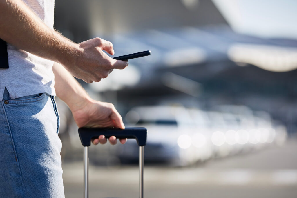 Passenger with phone and luggage at Stansted Airport transfer pickup
